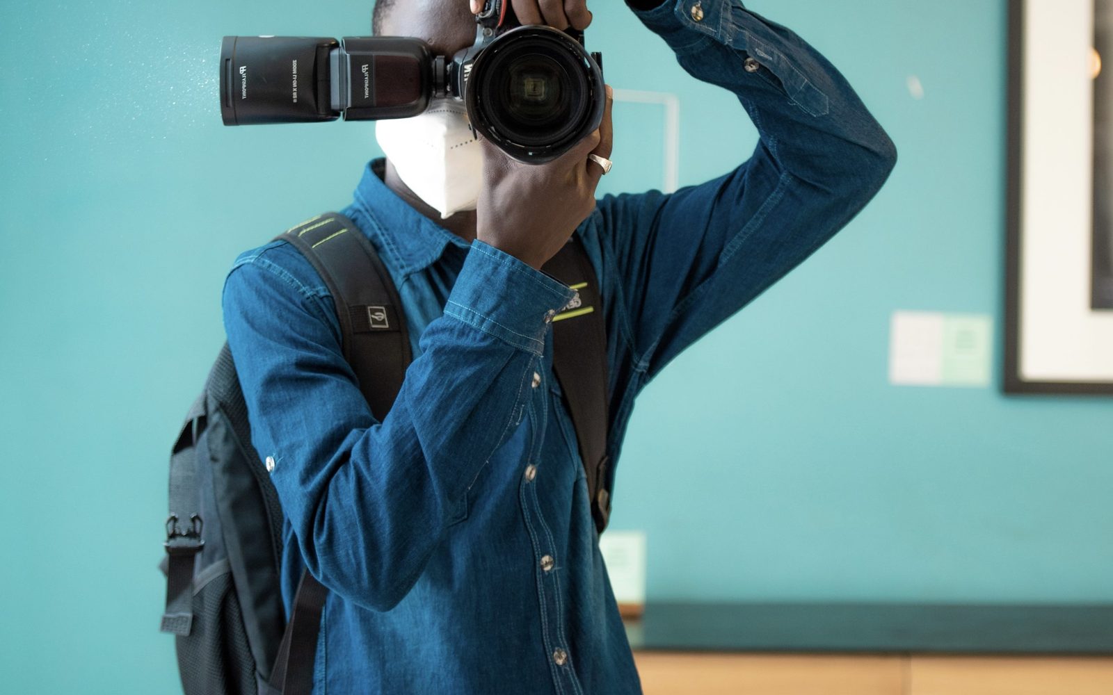 Photographe cadrant avec son appareil photo devant un mur bleu